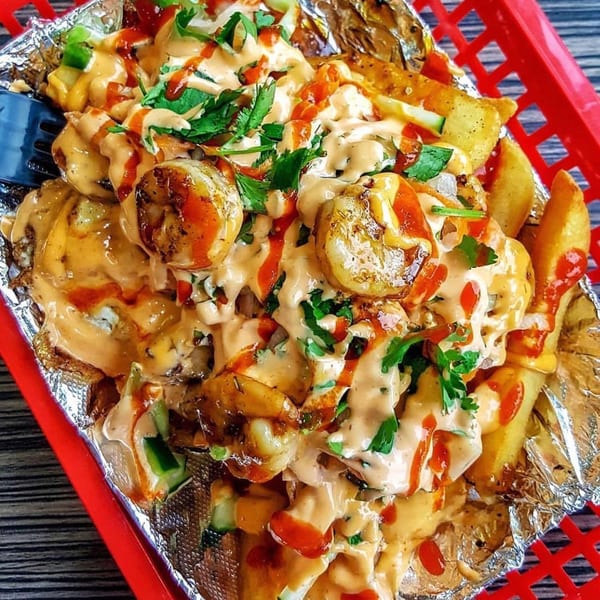 YUMMI BANH MI STREETSIDE CAFÈ's loaded fries with shrimp, sauce, and cilantro in a red basket.