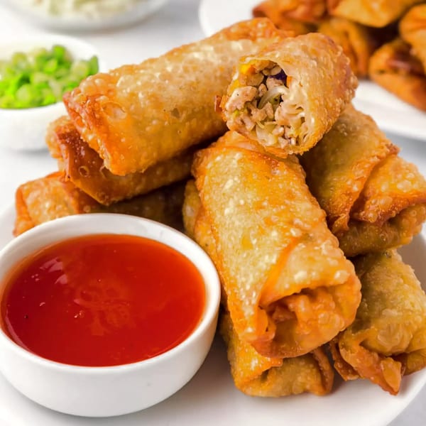Crispy Vietnamese egg rolls with savory filling, served with a side of sweet chili dipping sauce.